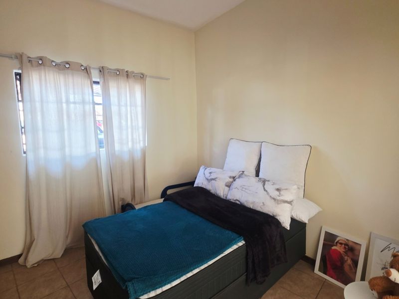 A functional bedroom featuring tiled flooring and a built-in wardrobe, providing essential storage space.