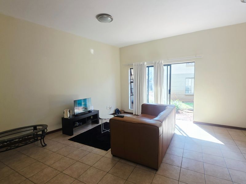 A spacious living room featuring neutral tiled flooring and a sliding glass door providing direct access to the outdoor area.