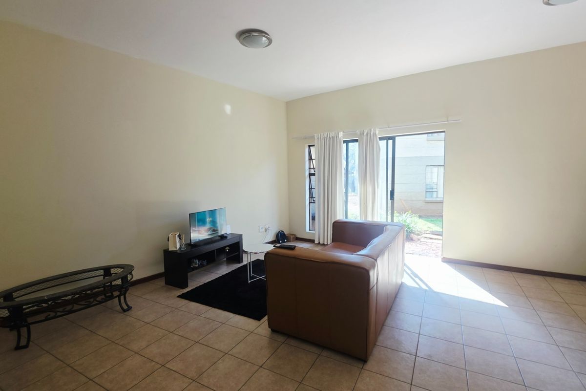 A spacious living room featuring neutral tiled flooring and a sliding glass door providing direct access to the outdoor area.