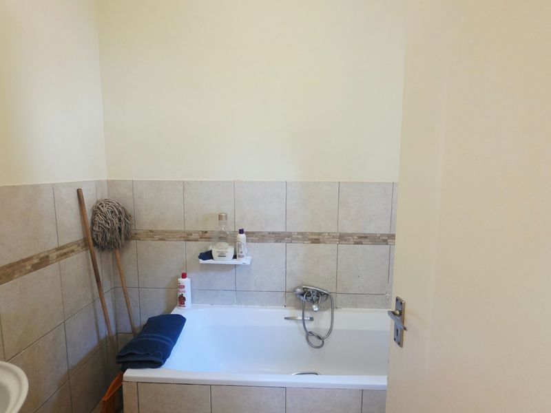 A functional bathroom featuring a bathtub with a mixer tap, tiled wall finishes, and a pedestal basin.