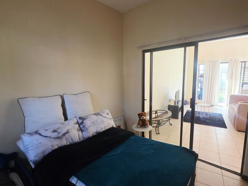 A bedroom featuring tiled flooring and a large sliding glass door that provides access to the adjacent living area.