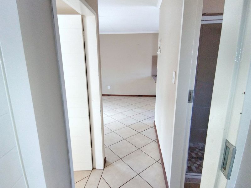 A neutral hallway with tiled flooring leading into an open living area, providing access to adjacent rooms.