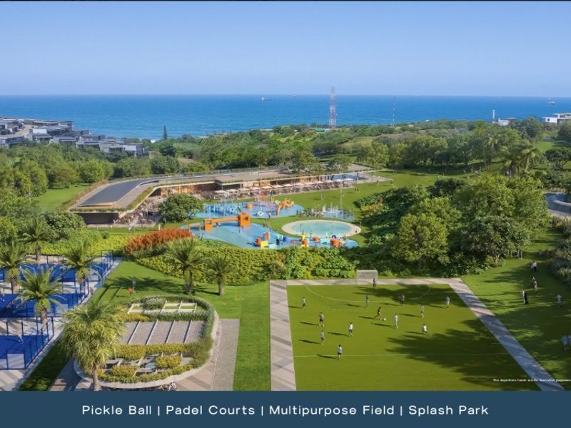 Aerial view of a residential estate featuring a splash park, multipurpose sports field, and dedicated pickleball and padel courts with ocean views.