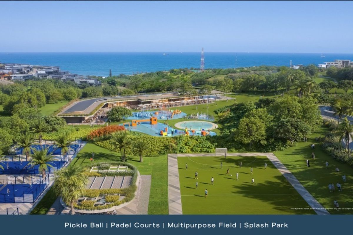 Aerial view of a residential estate featuring a splash park, multipurpose sports field, and dedicated pickleball and padel courts with ocean views.