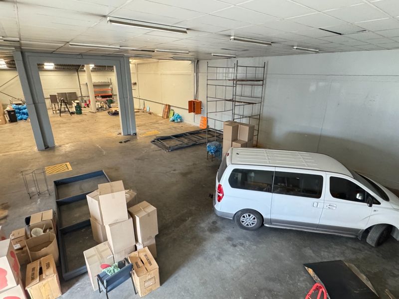 Spacious industrial utility area featuring concrete flooring, steel support columns, and suspended ceiling lighting, suitable for storage or workshop operations.
