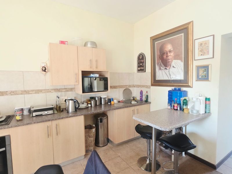 A functional kitchen featuring light wood cabinetry, laminate countertops, a tiled backsplash, and integrated cooking appliances with an attached breakfast bar area.