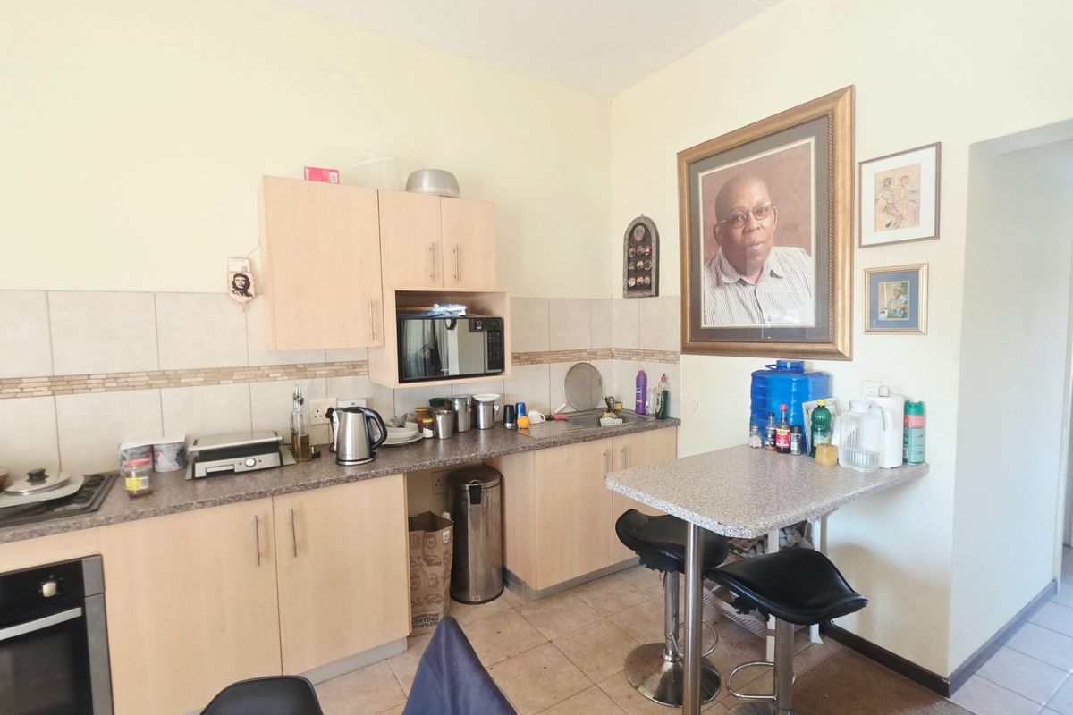 A functional kitchen featuring light wood cabinetry, laminate countertops, a tiled backsplash, and integrated cooking appliances with an attached breakfast bar area.