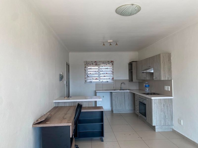 Open-plan kitchen area featuring modern wood-look cabinetry, built-in oven, extractor fan, and tiled flooring, providing a functional space for cooking and dining.