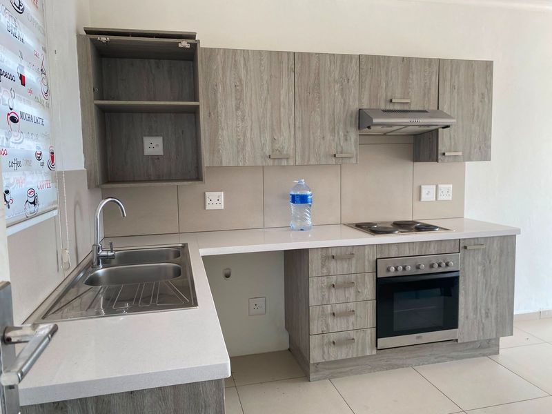 Modern kitchen featuring wood-look cabinetry, stone countertops, a double bowl sink, and integrated electric oven and hob with an extractor fan.