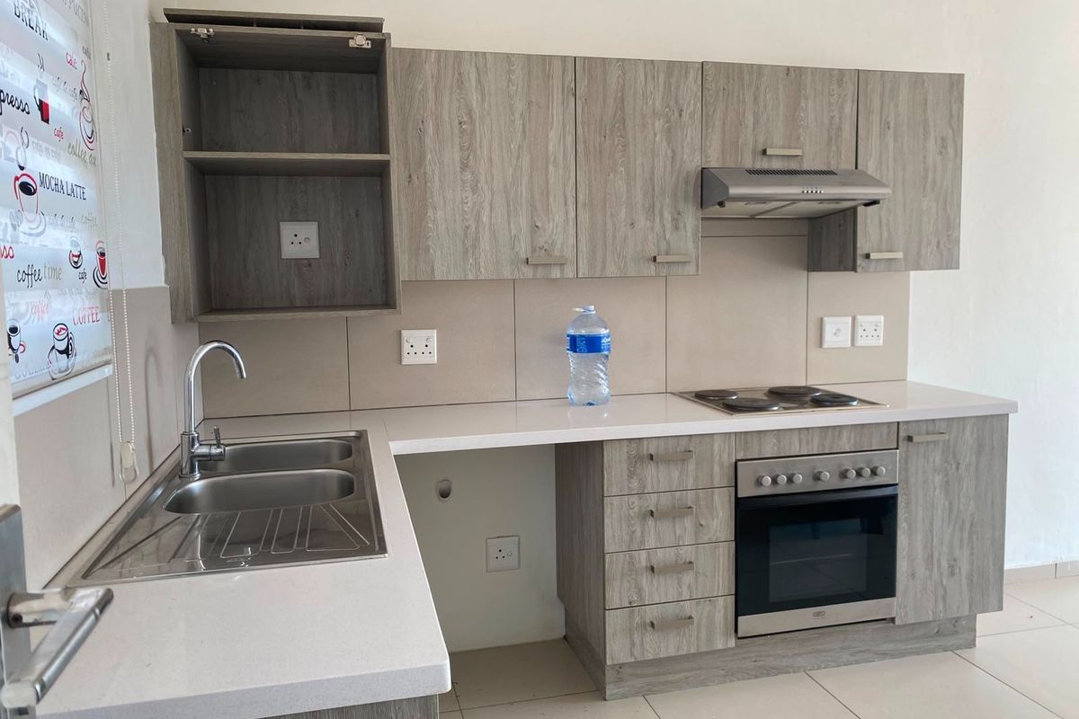 Modern kitchen featuring wood-look cabinetry, stone countertops, a double bowl sink, and integrated electric oven and hob with an extractor fan.