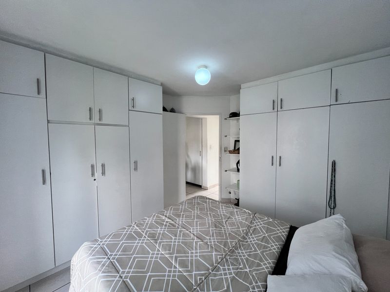 Bedroom featuring extensive white built-in cupboards providing ample storage space and integrated shelving units.
