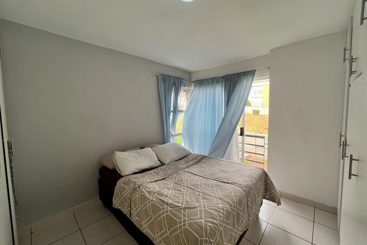 A bedroom featuring tiled flooring, built-in cupboards, and a sliding glass door providing access to an outdoor area.
