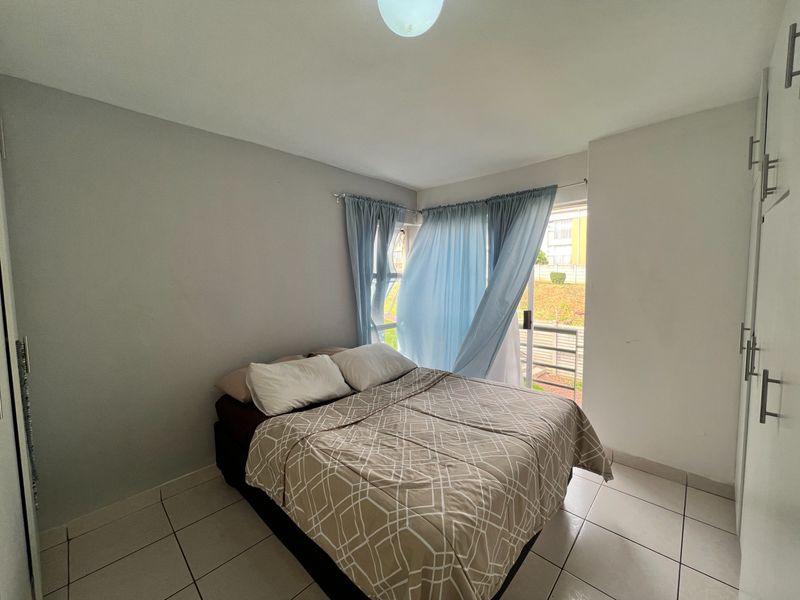 A bedroom featuring tiled flooring, built-in cupboards, and a sliding glass door providing access to an outdoor area.