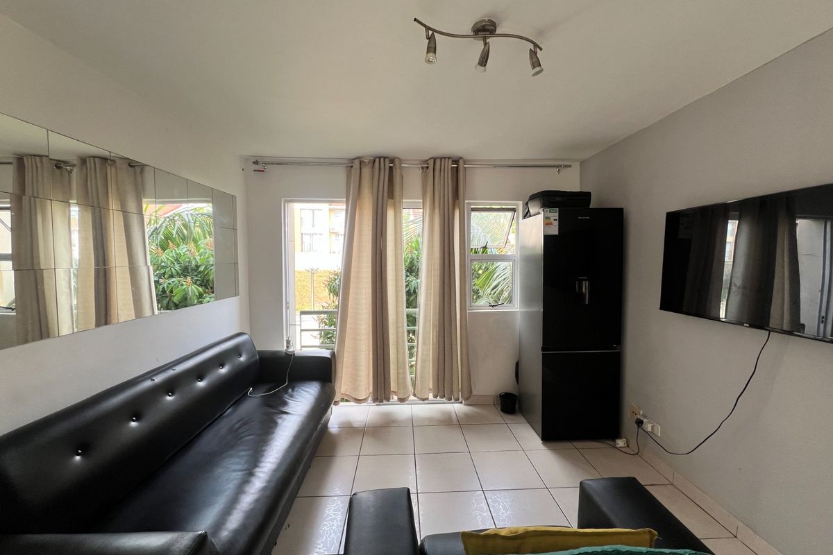 A living room featuring tiled flooring, a wall-mounted mirror, and a sliding glass door providing access to the exterior.
