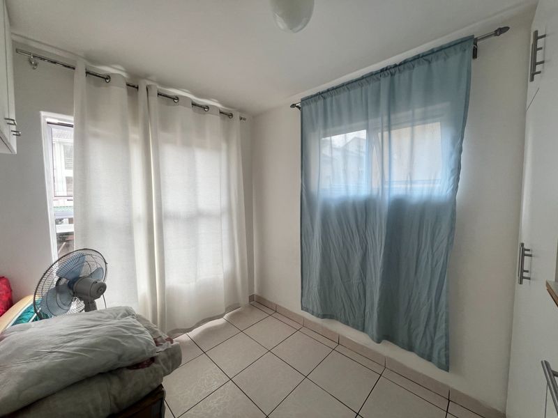 A bright, empty bedroom featuring tiled flooring and built-in cabinetry, offering a clean and neutral space ready for personalization.