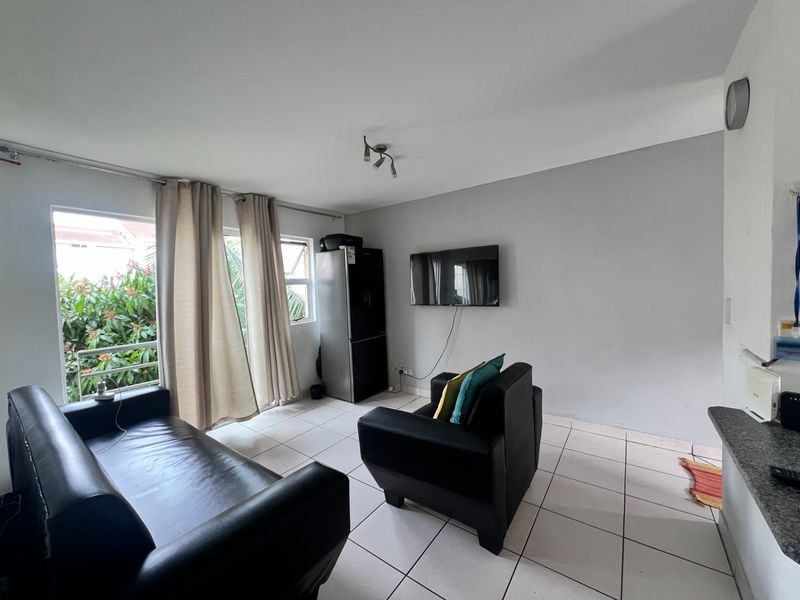 A living room area featuring tiled flooring, a sliding glass door providing natural light, and a granite breakfast bar counter.