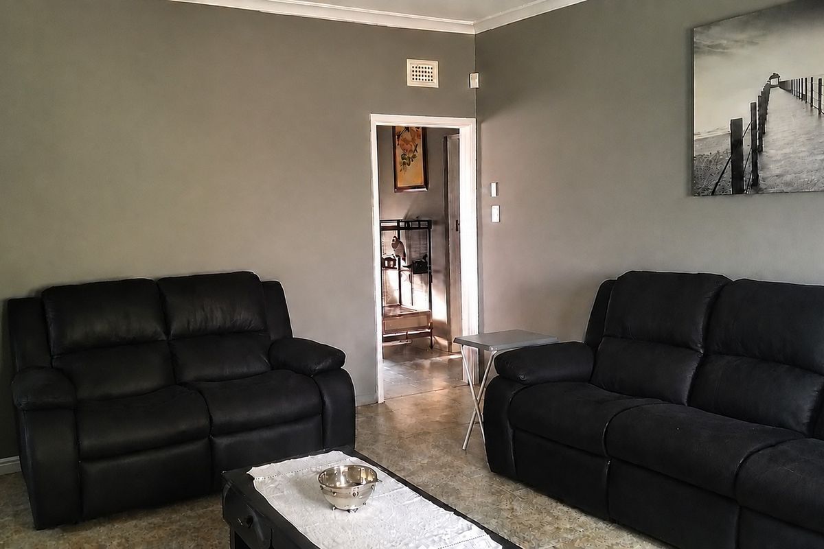 A living room featuring grey painted walls, tiled flooring, and a doorway leading to an adjacent space.