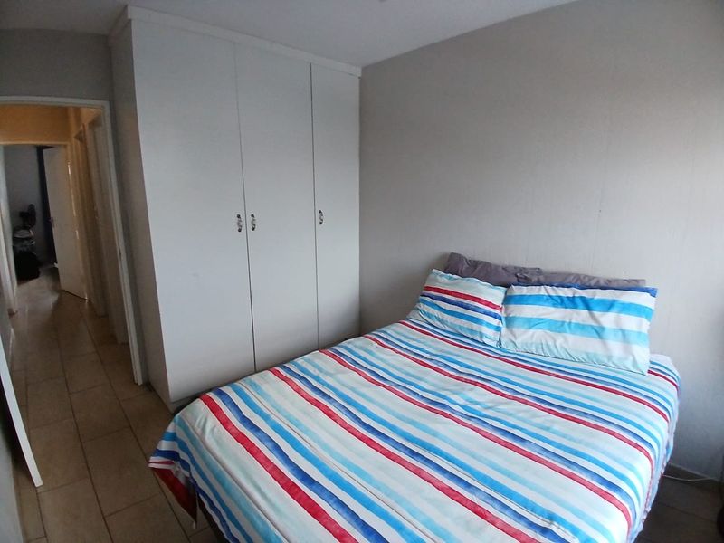 A functional bedroom featuring built-in wardrobes and tiled flooring, providing a practical and neutral space for rest.