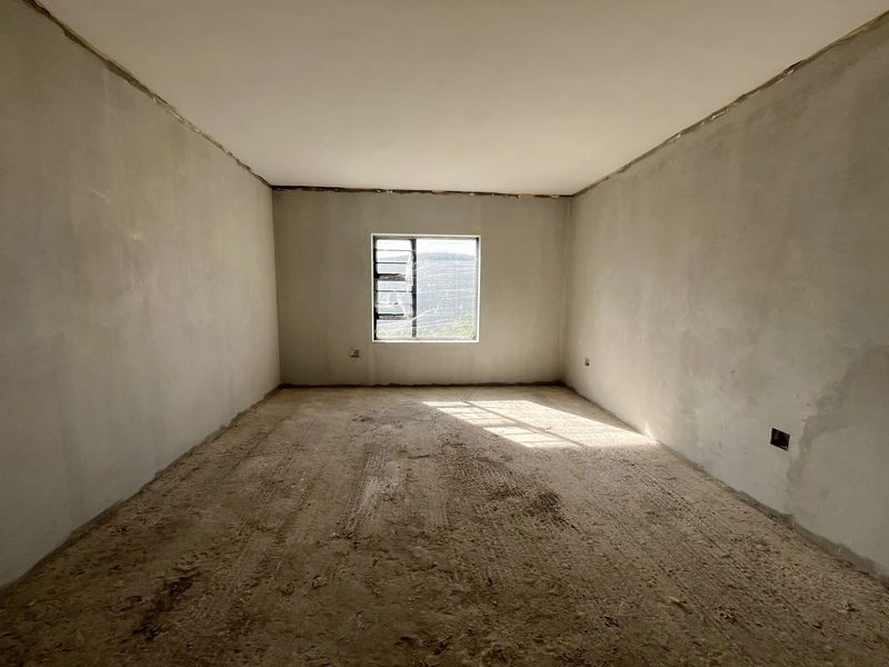 An unfinished bedroom space featuring raw plaster walls, an exposed floor surface, and a louvered window with a cracked pane.