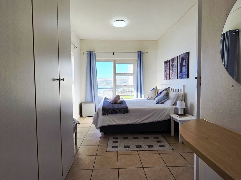 A bedroom featuring built-in cupboards, tiled flooring, and a sliding glass door that provides natural light and access to the exterior.