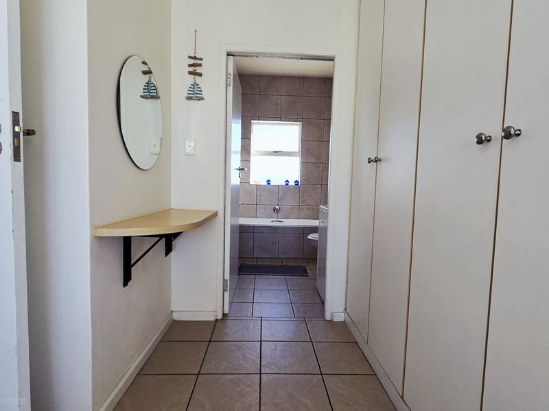 A functional hallway featuring built-in cupboards and tiled flooring, providing direct access to an adjacent bathroom.