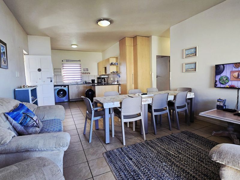 Open-plan living and dining area featuring tiled floors and an integrated kitchen with built-in cabinetry and laundry facilities.