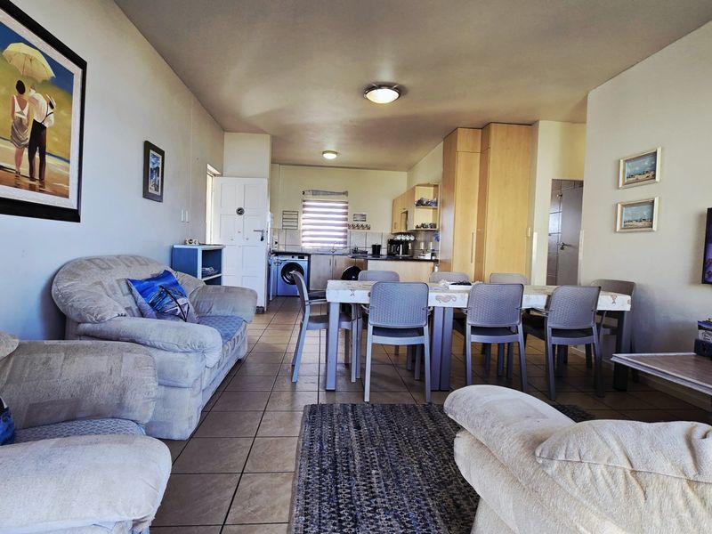 An open-plan living, dining, and kitchen area featuring tiled flooring and functional built-in cabinetry, offering a practical layout for daily living.