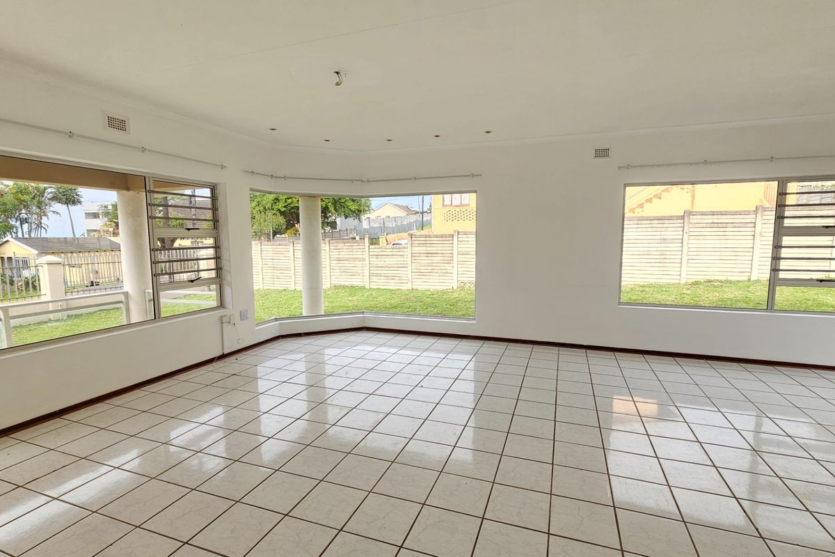 Spacious, light-filled living area featuring large windows, neutral tiled flooring, and recessed lighting, offering a blank canvas for interior design.