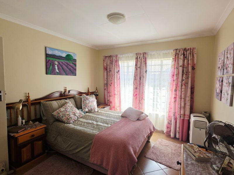 A well-lit bedroom featuring tiled flooring and neutral wall finishes, providing a comfortable and functional living space.