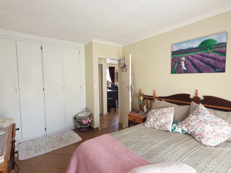 A bedroom featuring built-in cupboards, tiled flooring, and coved ceilings, offering a functional space with neutral wall tones.