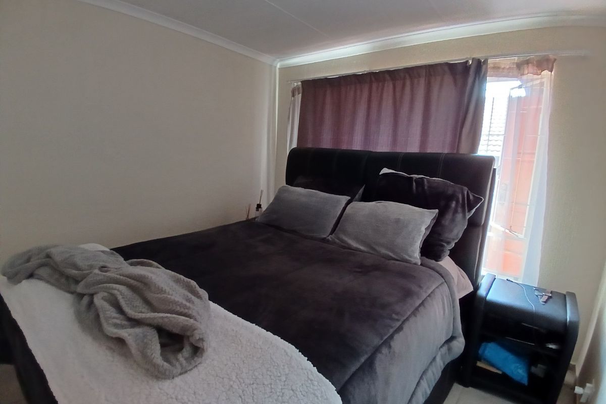 A standard bedroom featuring tiled flooring and cove cornicing, providing a functional space with natural light from the window.