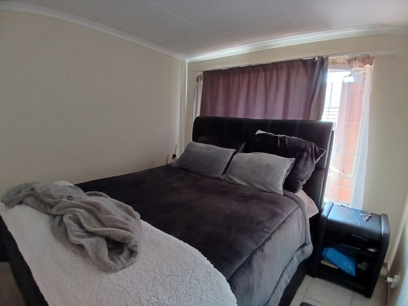 A standard bedroom featuring tiled flooring and cove cornicing, providing a functional space with natural light from the window.