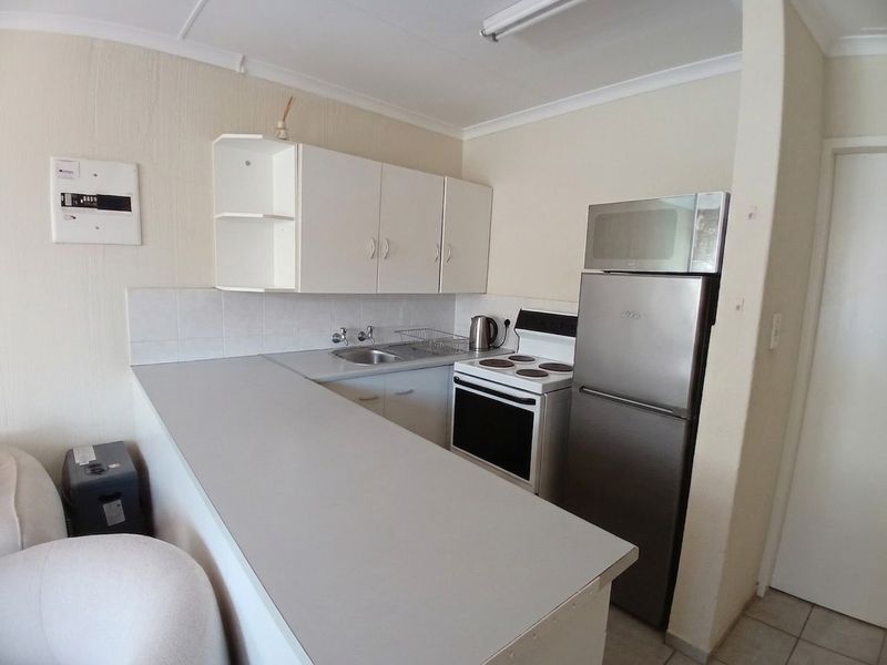 Compact kitchen featuring white cabinetry, laminate countertops, a stainless steel sink, and a freestanding stove, offering a functional layout for a townhouse.