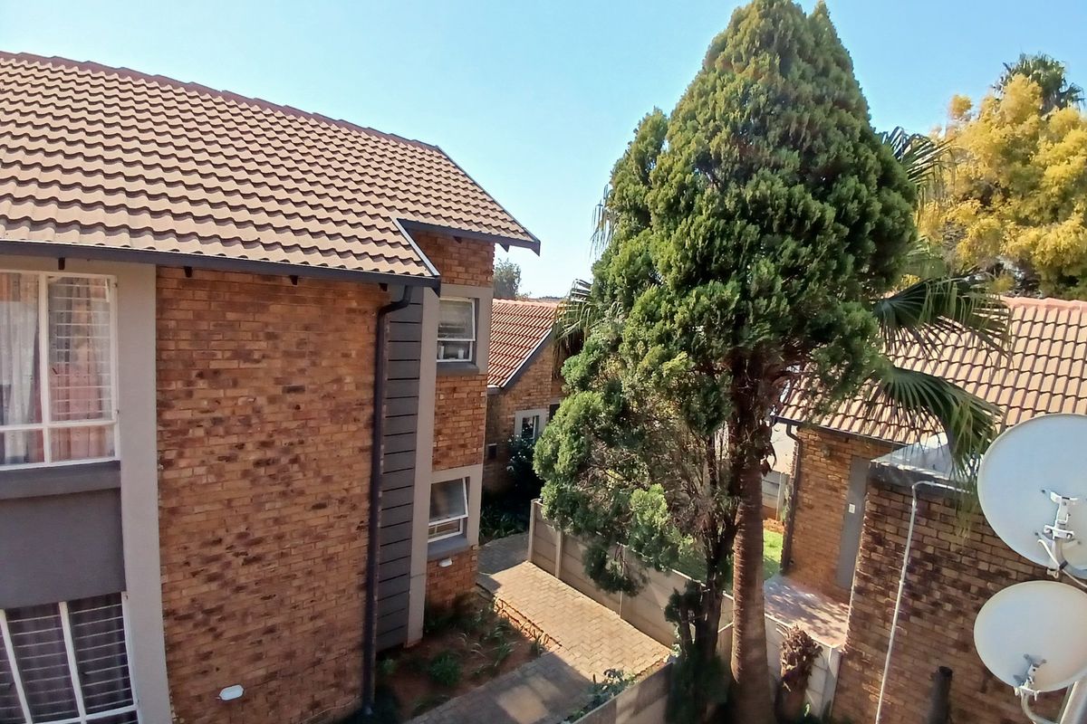 An elevated view of the townhouse complex exterior, featuring face-brick facades, tiled roofing, and paved pathways between units.