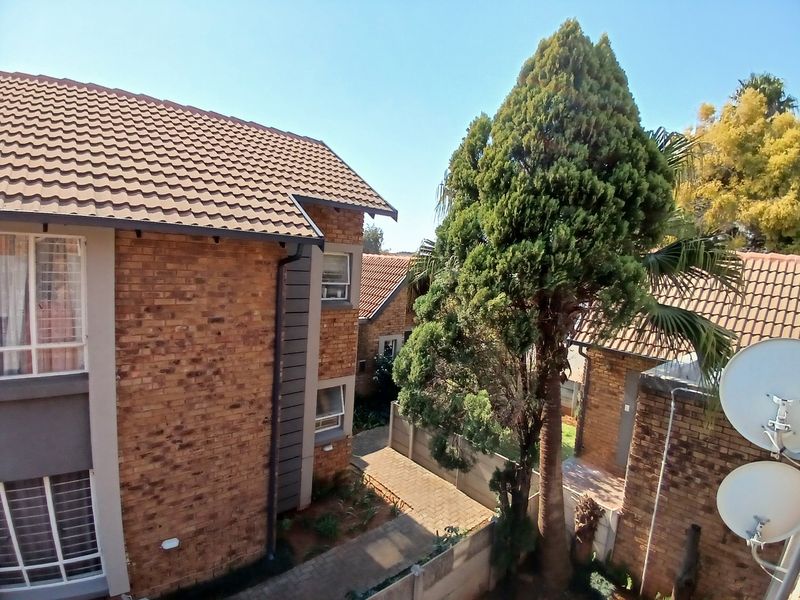 An elevated view of the townhouse complex exterior, featuring face-brick facades, tiled roofing, and paved pathways between units.