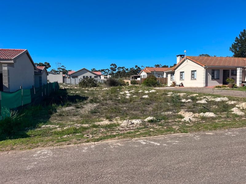 A vacant residential plot situated between existing homes, featuring direct road access and established boundary fencing in a suburban neighborhood.