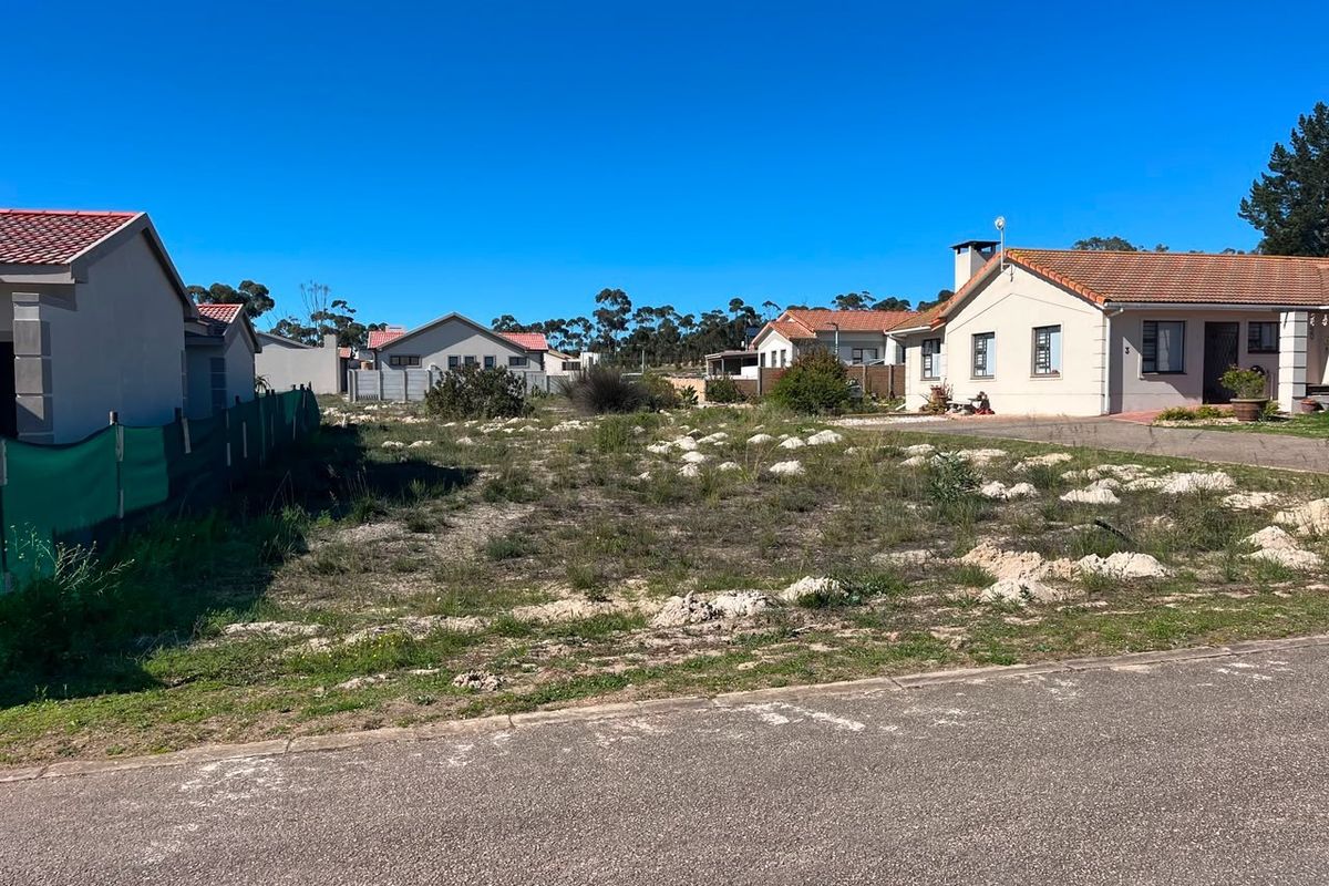 A vacant residential plot situated between existing homes, featuring direct road access and established boundary fencing in a suburban neighborhood.