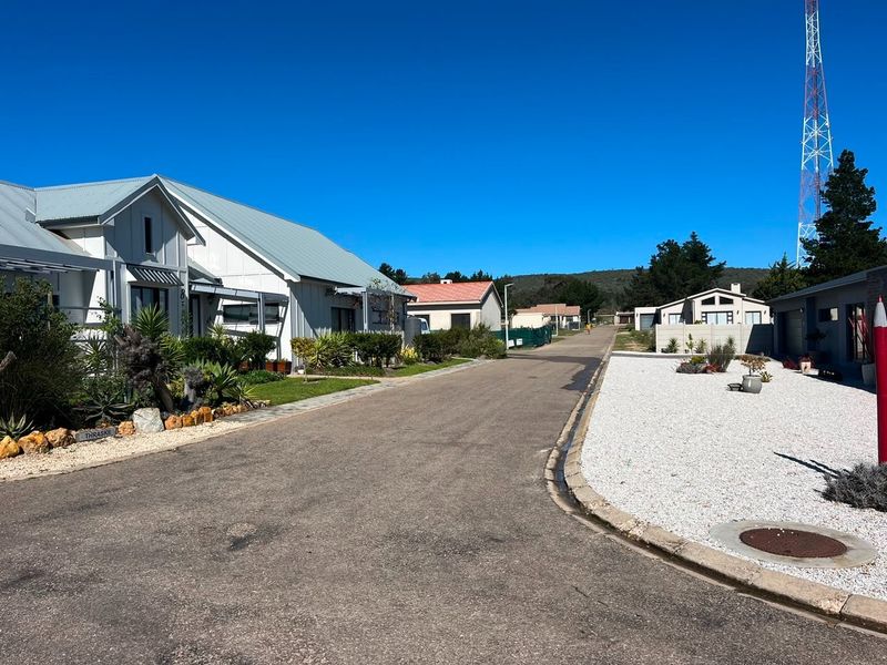 A clear street view of a residential neighborhood featuring paved roads, gravel landscaping, and surrounding residential properties under a clear blue sky.