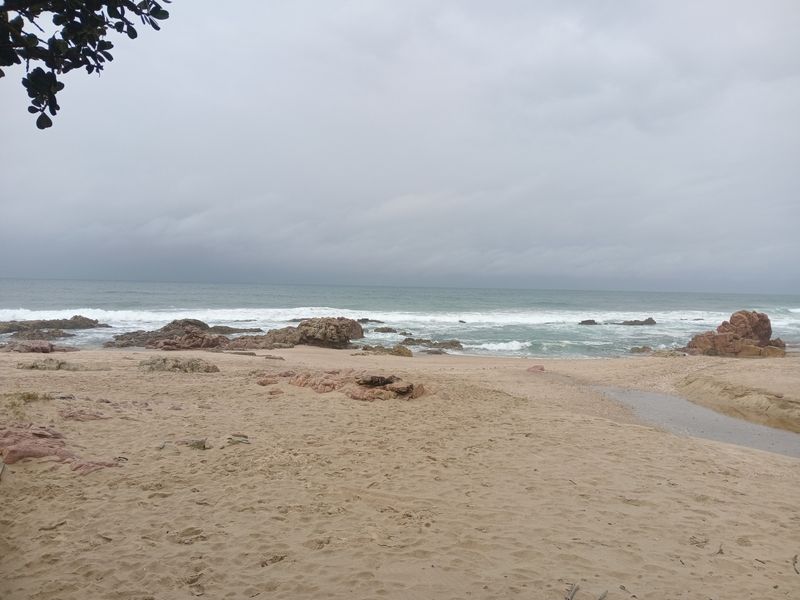 A scenic view of the sandy beach and rocky coastline, showcasing the natural landscape and ocean frontage of the property.