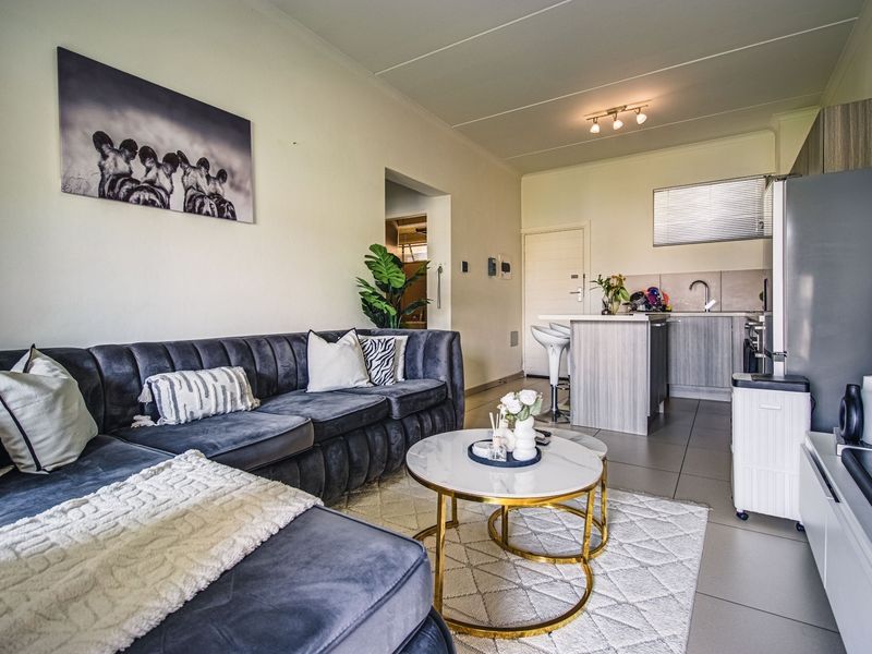 An open-plan living area featuring a modern kitchen with island, tiled flooring, and neutral finishes, creating a functional and cohesive living space.