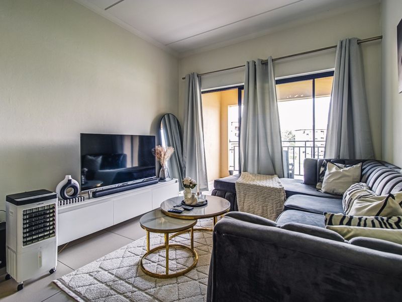 A well-lit living room featuring tiled floors and a large sliding glass door that provides access to an outdoor balcony area.