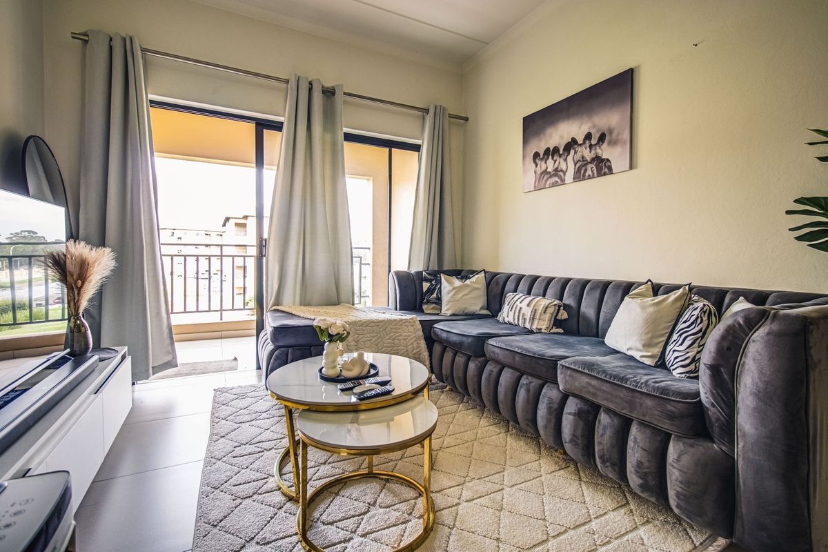 A well-lit living room featuring tiled floors and a sliding glass door providing direct access to an outdoor balcony.