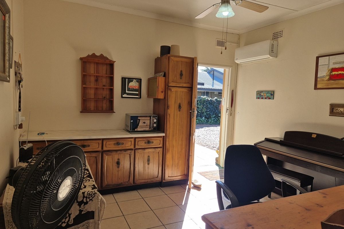 A functional living space featuring tiled flooring, a ceiling fan, split-system air conditioning, and built-in wooden cabinetry with direct access to the exterior.