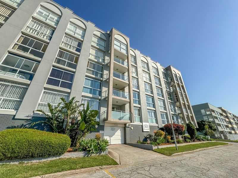 Front elevation of The Palladium apartment complex, featuring multi-story residential units with balconies, glass balustrades, and established landscaped garden areas.