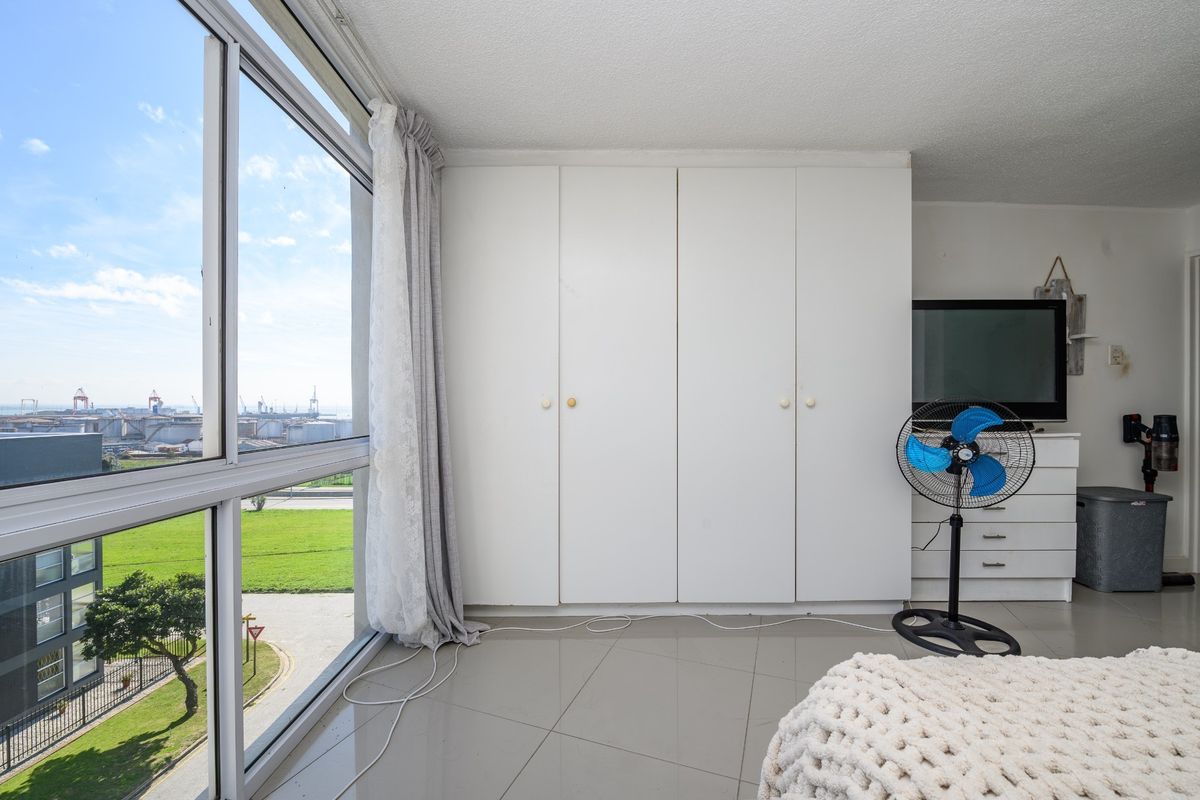 Bedroom featuring built-in cupboards, large floor-to-ceiling windows with expansive views, and tiled flooring.