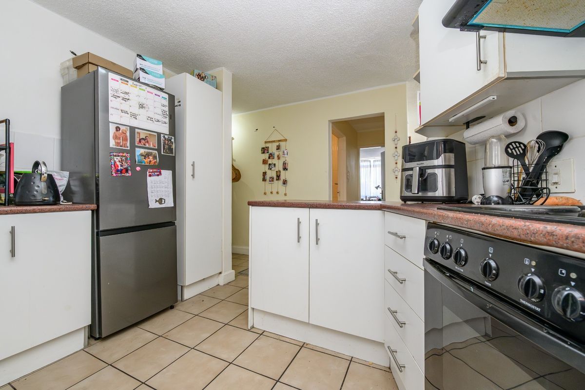 Functional kitchen featuring laminate countertops, white cabinetry, tiled flooring, and a freestanding oven, offering a practical layout for daily meal preparation.