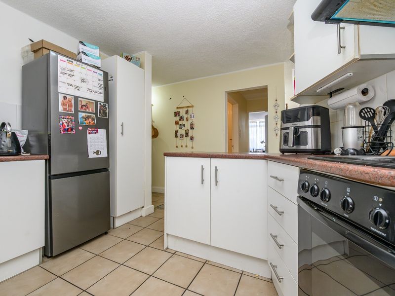 Functional kitchen featuring laminate countertops, white cabinetry, tiled flooring, and a freestanding oven, offering a practical layout for daily meal preparation.