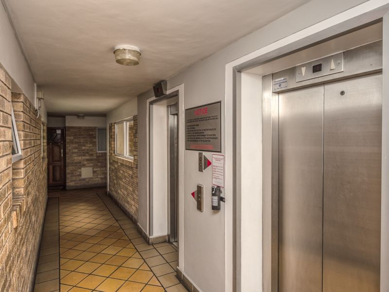 A communal apartment hallway featuring brick wall finishes, tiled flooring, and access to an elevator.