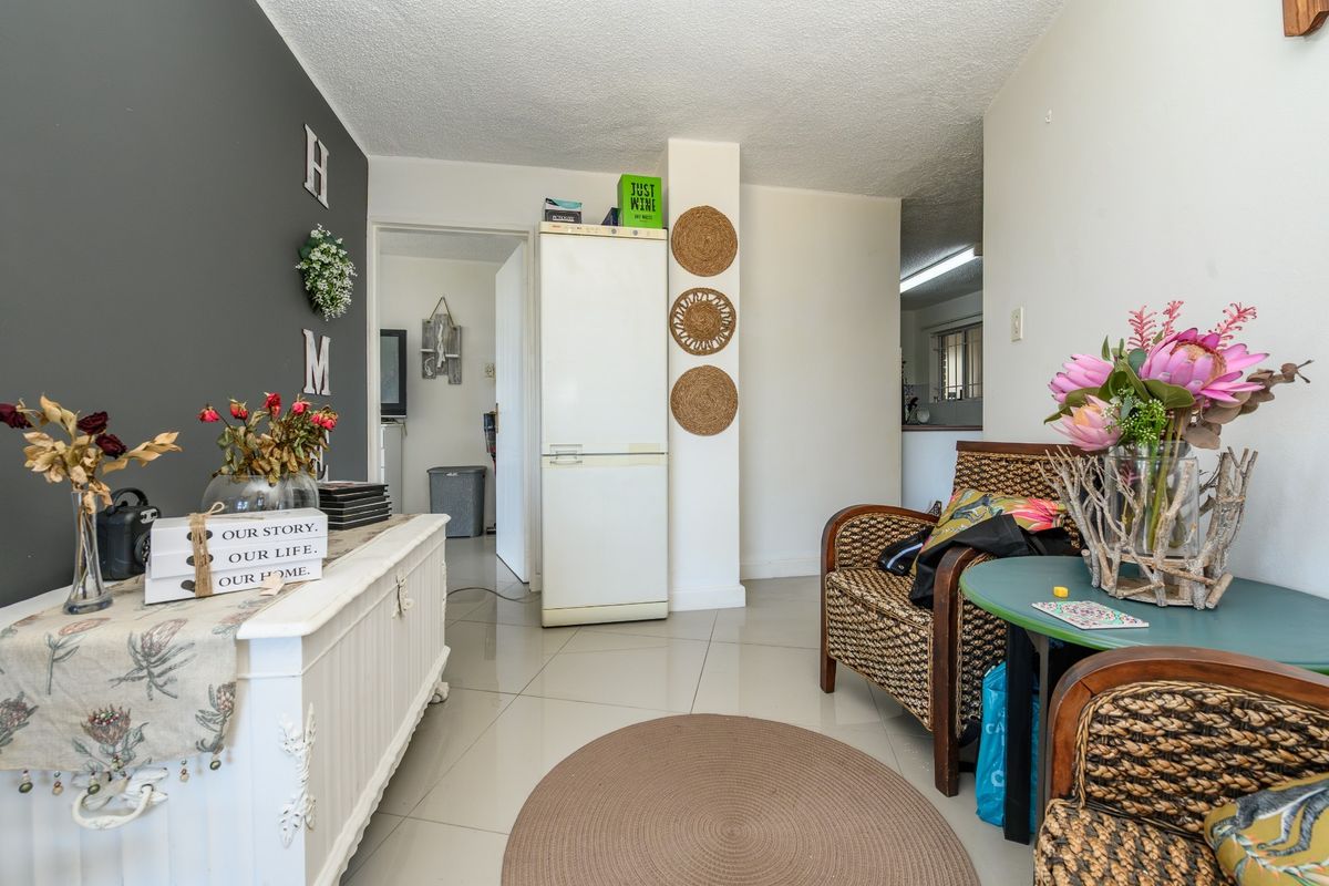 A living area featuring tiled flooring and a neutral color palette, providing a functional space with access to adjacent rooms.