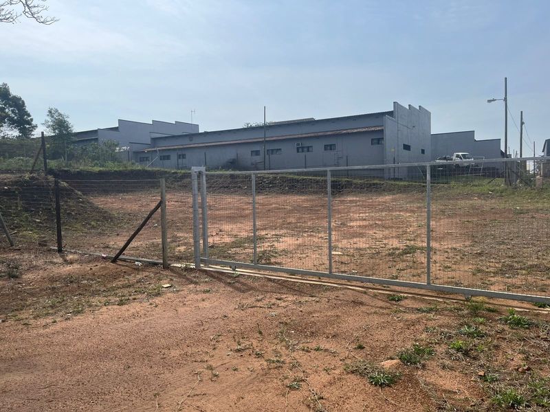 A vacant agricultural land plot featuring chain-link perimeter fencing and a metal sliding gate, providing clear access to the site.